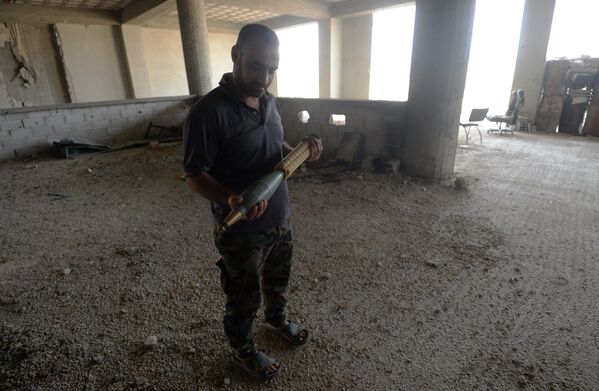 Военнослужащий ополчения Сирийской Арабской армии демонстрирует снаряд на позиции в одном из домов в районе Джобар в Дамаске