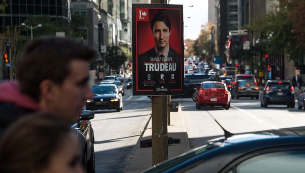 Люди проходят мимо плаката лидера канадской либеральной партии Джастин Трюдо в Монреале