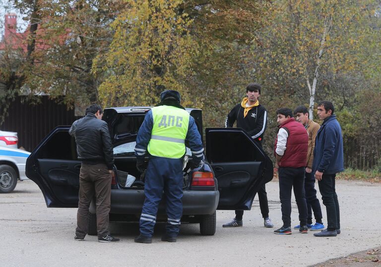 Сотрудник ДПС досматривает машину автовладельца на одной из улиц деревни Тимошкино