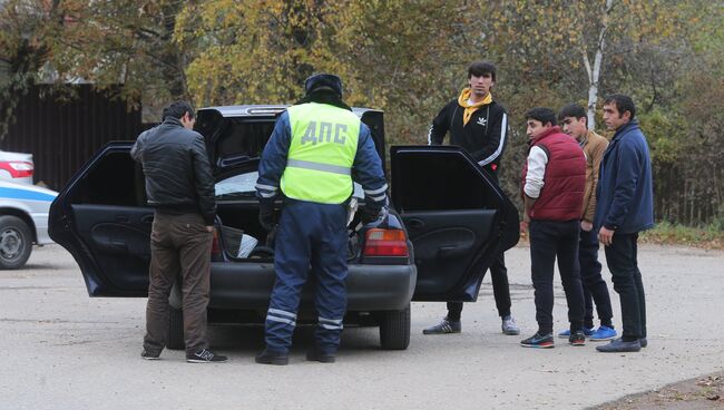 Сотрудник ДПС досматривает машину автовладельца на одной из улиц деревни Тимошкино