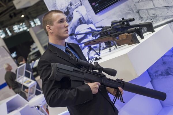 Сотрудник со снайперской крупнокалиберной бесшумной винтовкой Выхлоп на стенде компании Ростех на международной выставке Интерполитех-2015 в Москве