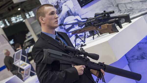 Сотрудник со снайперской крупнокалиберной бесшумной винтовкой Выхлоп на стенде компании Ростех на международной выставке Интерполитех-2015 в Москве
