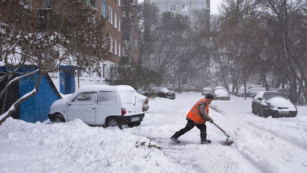 Сотрудник коммунальных служб убирает заснеженные улицы города Омска