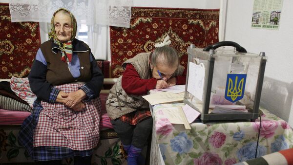 Женщины заполняют избирательные бюллетени во время выборов в поселке Сартана Донецкой области, Украина