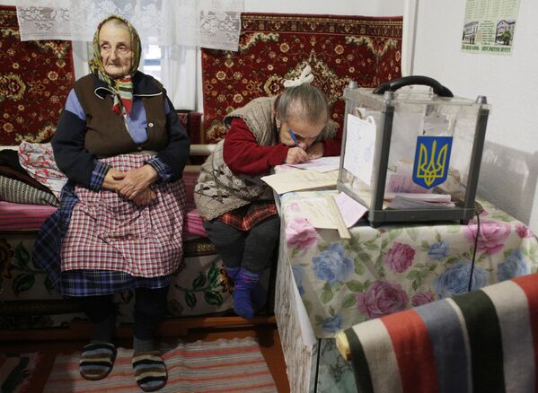 Женщины заполняют избирательные бюллетени во время выборов в поселке Сартана, Донецкая область