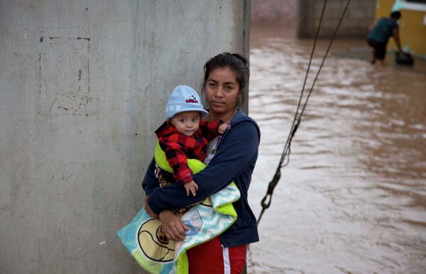 Мать с ребенком ожидают помощи спасателей в городе Зоатлан, Мексика