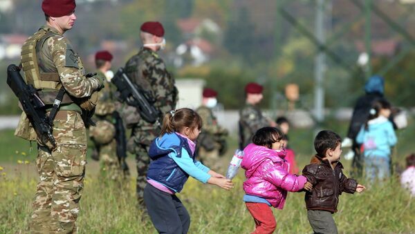 Дети беженцев играют рядом со словенскими военными на хорватско-словенской границе. Архивное фото