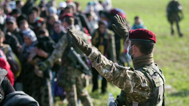 Словенский военный управляет движением беженцев, прибывших из Хорватии, архивное фото