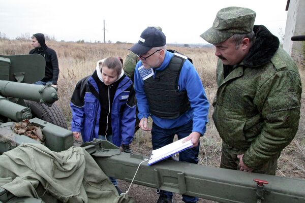Представители ОБСЕ у военной техники, отведенной от линии соприкосновения ДНР, на специально подготовленной площадке в Донецкой области