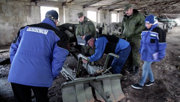 Представители ОБСЕ у военной техники, отведенной от линии соприкосновения ДНР, на специально подготовленной площадке в Донецкой области