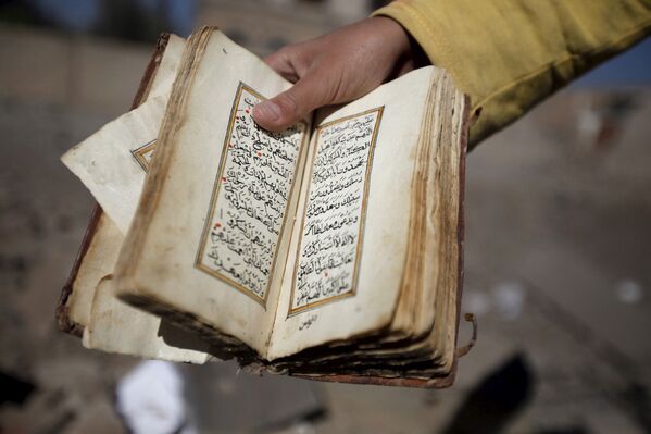 Ребенок держит сборник мусульманских молитв, найденный в разрушенном в результате авиаударов доме в Сане, Йемен