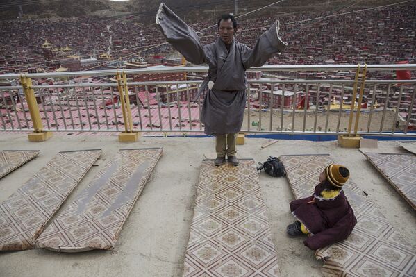 Тибетец молится в монастыре у института буддизма Ларунг Гар, Тибетский автономный район, КНР