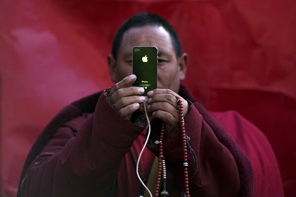 Буддистский монах снимает на смартфон во время дневных песнопений, Тибетский автономный район, КНР