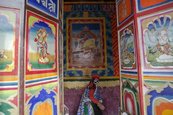 Тибетская женщина под изображением ламы Кэнпо Джигме Фунтсока в институте буддизма Ларунг Гар, Тибетский автономный район, КНР