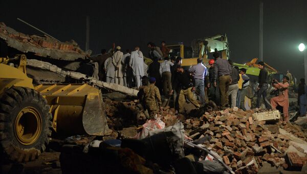 Пакистанские спасатели на месте разрушенного завода на окраине Лахора