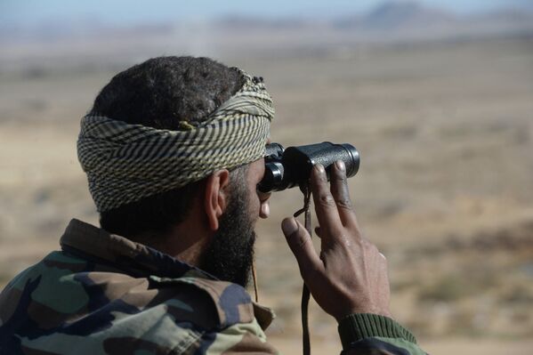 Солдат 18 дивизии 3 корпуса Сирийской Арабской Армии (САА) наблюдает за боевыми позициями боевиков в 20 километрах от города Пальмира
