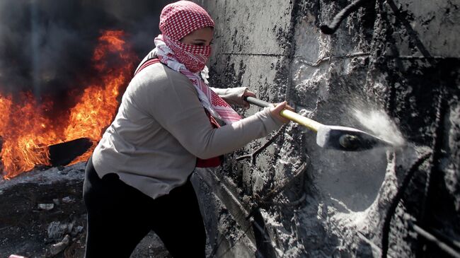 Палестинская женщина пытается разрушить разделительную стену на Западном берегу Абу-Дис