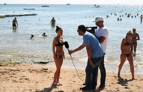 Съемочная группа берет интервью у туристки на берегу курорта Красного моря в Шарм-эш-Шейхе