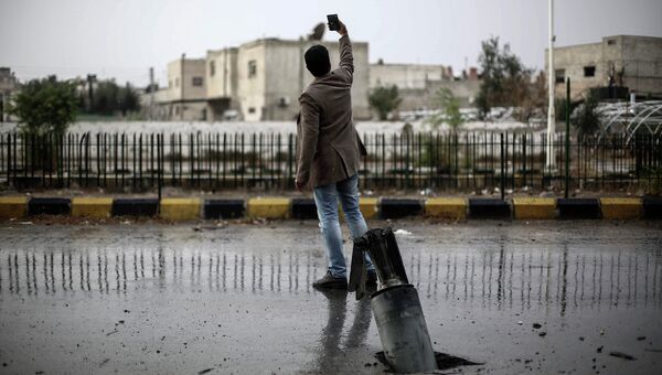 Житель Сирии делает на фоне снаряда в городе Дума. Сирия, ноябрь 2015