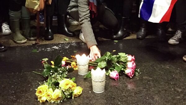 Люди возлагают цветы в Монреале в знак солидарности семьям погибших и пострадавших в терактах в Париже, 14 ноября 2015