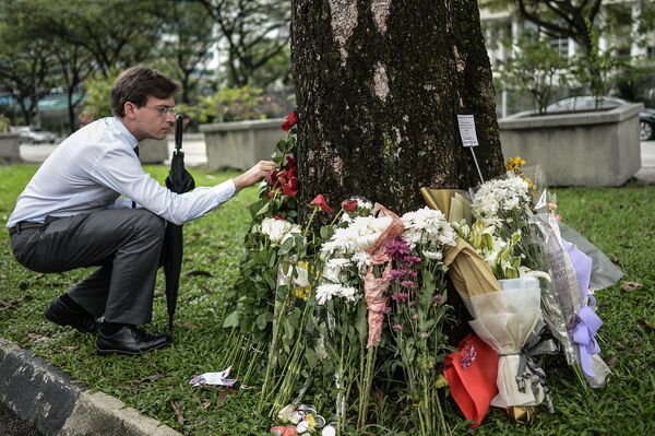 Мужчина кладет цветы у посольства Франции в Куала-Лумпуре, в память о жертвах крупнейшего в истории Франции террористического акта, произошедшего 13 ноября 2015 года в Париже