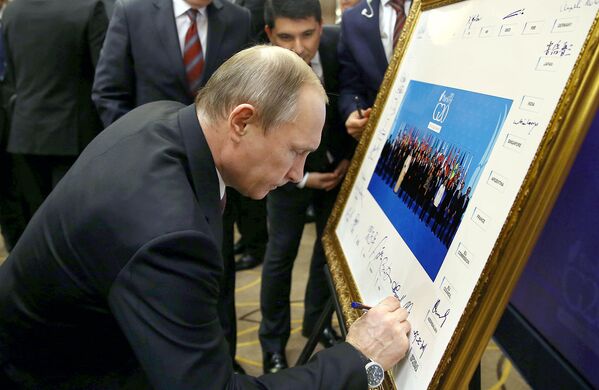 Президент России Владимир Путин подписывает общую фотографию лидеров саммита G20 в Турции