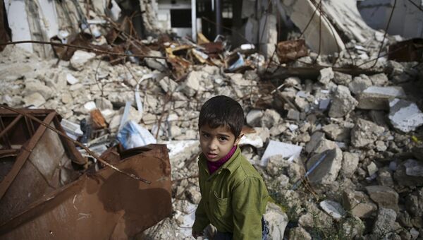 Мальчик среди разрушенных зданий в городе Дума, Дамаск. Сирия, ноябрь 2015