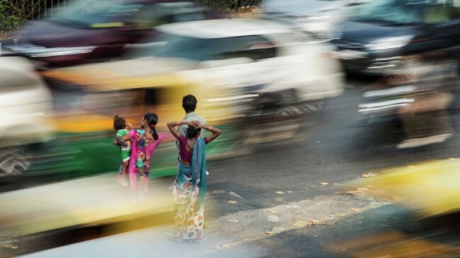 Люди стоят на разделительной полосе в час пик в Нью-Дели