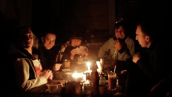 Люди сидят при свечах на кухне в своем доме. Архивное фото