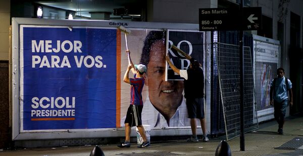 Служащие заклеивают изображение аргентинского политического деятеля Даниэля Сциоли, который признал поражение в президентских выборах в Буэнос-Айресе, Аргентина