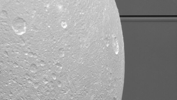 Крупный портрет Дионы на фоне колец Сатурна