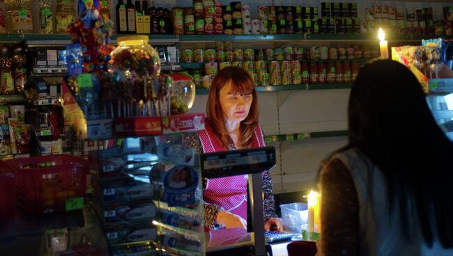Продавщица торгует при свечах в магазине в селе Чистенькое недалеко от Симферополя. Архивное фото