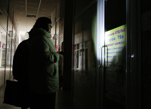 Женщина у закрытого, из-за отсутствия электричества, ателье по ремонту одежды в Симферополе