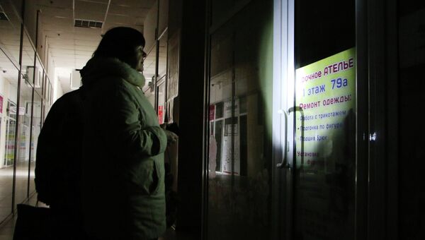 Женщина у закрытого, из-за отсутствия электричества, ателье по ремонту одежды в Симферополе. Архивное фото