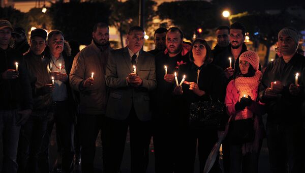 Члены партии Nidaa Tounes держат цветы и свечи в память о жертвах взрыва автобуса в центре Туниса