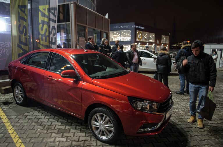 Молодые люди осматривают автомобиль Lada Vesta после начала продаж в Москве