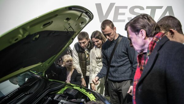 Посетители осматривают моторный отсек автомобиля Lada Vesta после начала продаж в Москве