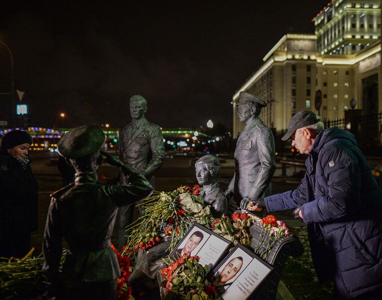 Портреты погибших в Сирии подполковника Олега Пешкова и матроса Александра Позынича и цветы у памятника героям фильма Офицеры