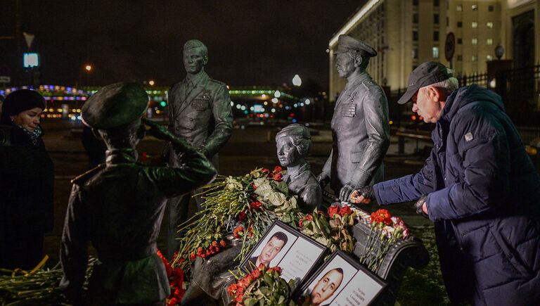 Портреты погибших в Сирии подполковника Олега Пешкова и матроса Александра Позынича и цветы у памятника героям фильма Офицеры