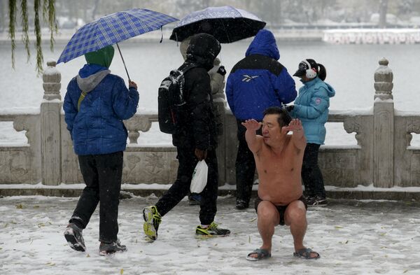 Мужчина делает гимнастику после купания в озере в Пекине