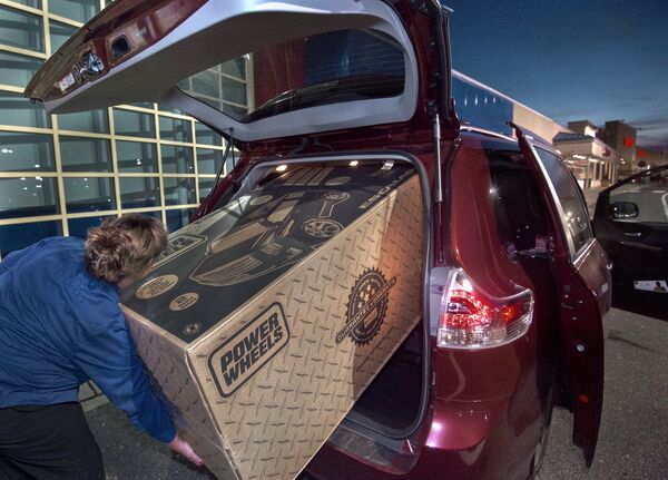 Сотрудник универмага помогает погрузить большую игрушку в автомобиль покупателя в Фэйрфаксе, США