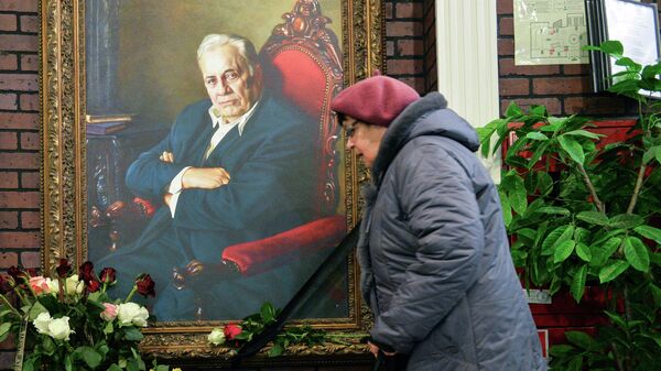 Женщина возлагает цветы к портрету народного артиста СССР режиссера Эльдара Рязанова