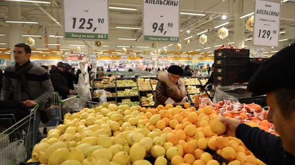 Покупатели у прилавка с лимонами и апельсинами из Турции в торговом зале гипермаркета Глобус