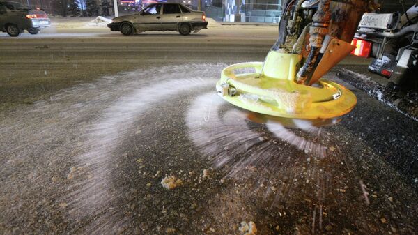 Спецтехника служб ЖКХ разбрасывает противогололедный материал во время снегопада на улицах