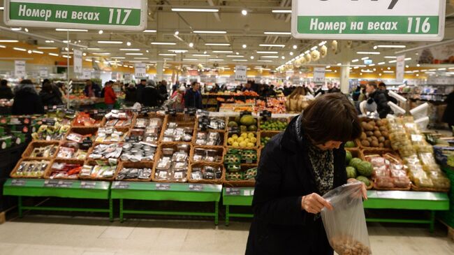 Покупательница у прилавка с орехами в торговом зале гипермаркета Глобус. Архивное фото