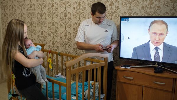 Молодая семья в Омске смотрит телевизионную трансляцию послания президента РФ Владимира Путина к Федеральному Собранию. Архивное фото