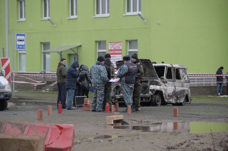 Представители правоохранительных органов осматривают место происшествия с полицейской машиной