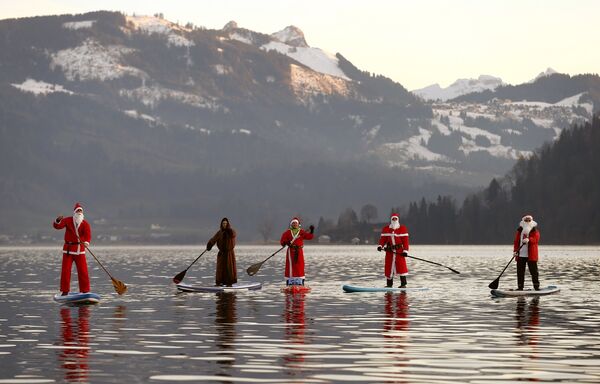 Люди в костюме Санта-Клауса переплывают озеро в Швейцарии
