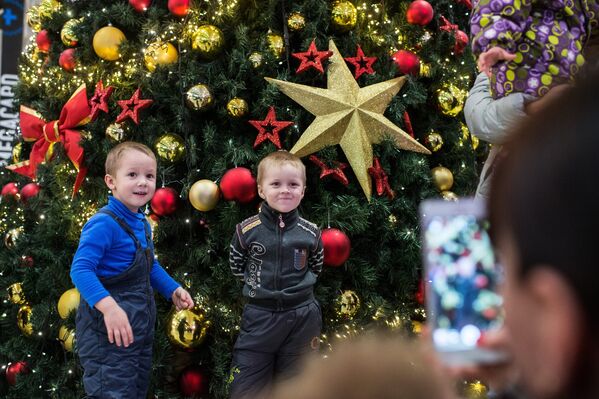 Дети фотографируются у новогодней ёлки в ожидании Деда Мороза из Великого Устюга в ТК Мега в Омске