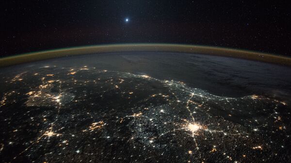Изображение Венеры на фоне ночных огней Земли, полученное с Международной космической станции